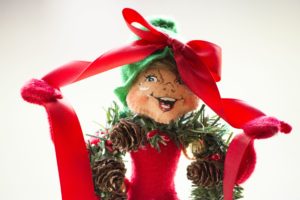 a christmas wreath wearing elf figure with a bow on it's head