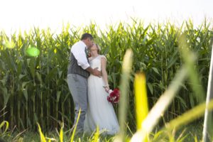 a couple at their wedding in a cornfield kissing